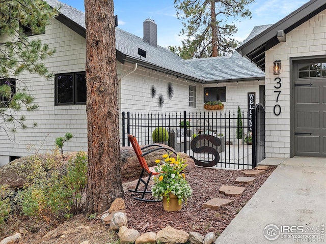 370 Big Boulder Dr, Estes Park, CO 80517 - view of home's exterior with roof with shingles, a chimney, concrete driveway, and an attached garage
