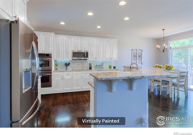 489 Hayloft Way, Brighton, CO 80601 - kitchen featuring appliances with stainless steel finishes, white cabinets, dark wood-type flooring, a breakfast bar area, and recessed lighting