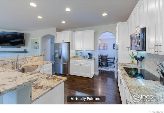 489 Hayloft Way, Brighton, CO 80601 - kitchen featuring appliances with stainless steel finishes, a sink, arched walkways, light stone countertops, and white cabinetry