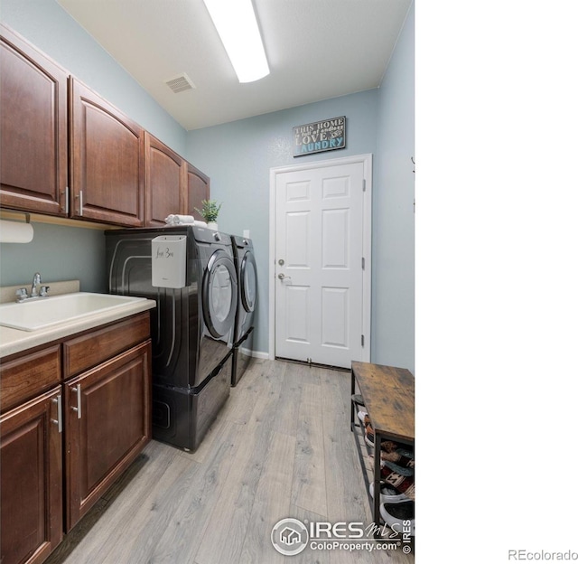 489 Hayloft Way, Brighton, CO 80601 - laundry room featuring washing machine and dryer, cabinet space, and light wood-style flooring
