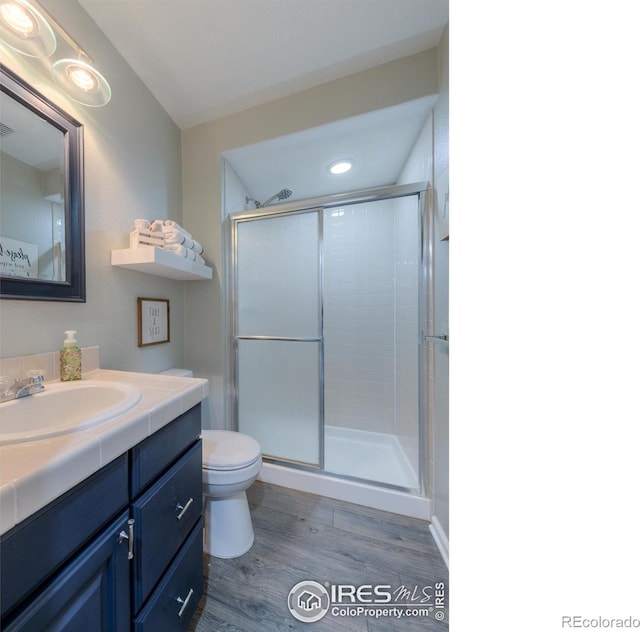 489 Hayloft Way, Brighton, CO 80601 - bathroom with a stall shower, wood finished floors, vanity, toilet, and recessed lighting