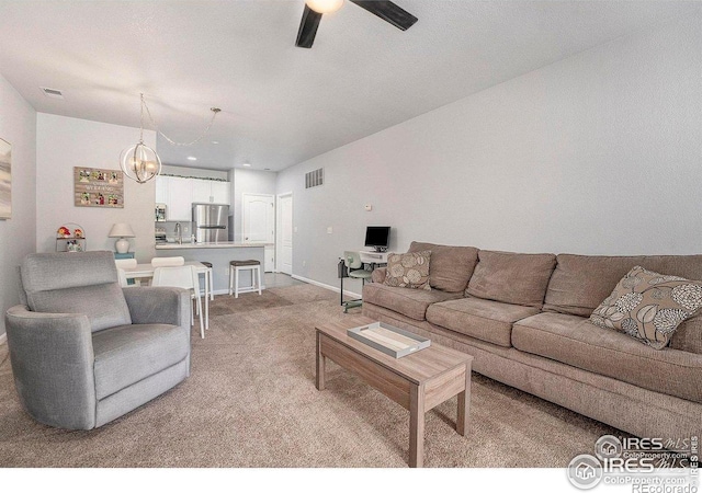 living room featuring light carpet, ceiling fan, and a chandelier