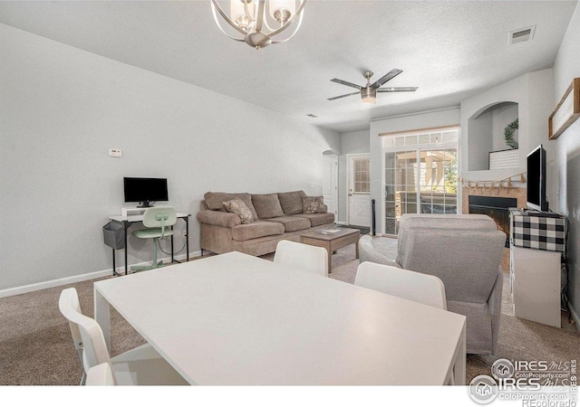 carpeted living area featuring a ceiling fan, a chandelier, baseboards, and a textured ceiling