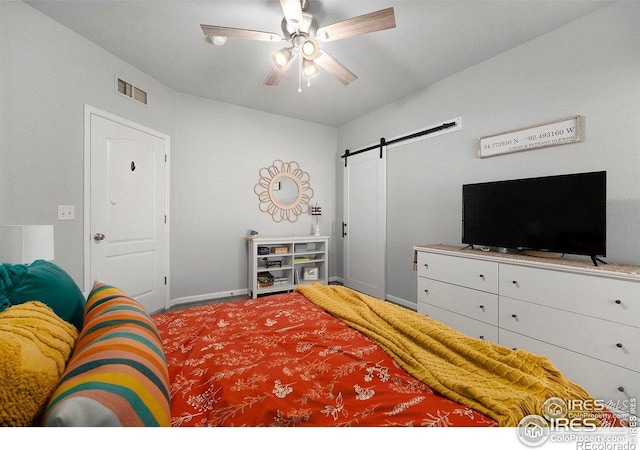 bedroom featuring a barn door, baseboards, and a ceiling fan