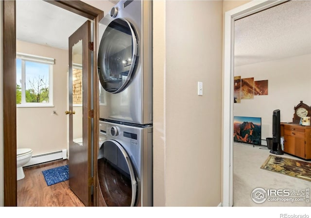 2709 Harvard St Unit 3, Fort Collins, CO 80525 - laundry area featuring a baseboard radiator, stacked washing machine and dryer, wood finished floors, and a textured ceiling