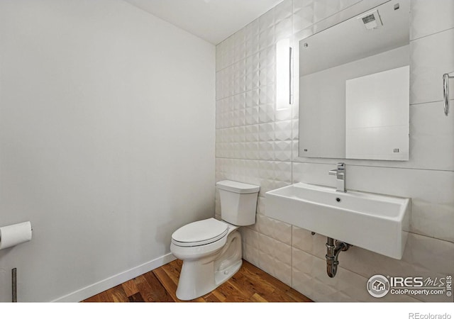 2625 W 25th Ave Unit 7, Denver, CO 80211 - half bathroom with tile walls, a sink, wood finished floors, and toilet