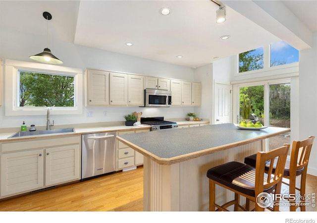 10481 Oxford Rd, Longmont, CO 80504 - kitchen featuring stainless steel appliances, a sink, a breakfast bar area, light wood-type flooring, and pendant lighting