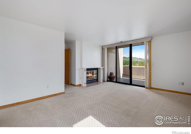 unfurnished living room with carpet, baseboards, and a glass covered fireplace