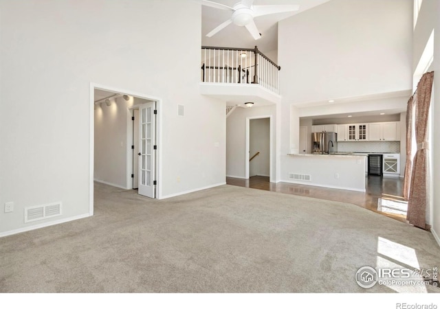 3227 Honeysuckle Ct, Fort Collins, CO 80521 - unfurnished living room featuring carpet floors, a ceiling fan, baseboards, a towering ceiling, and beverage cooler