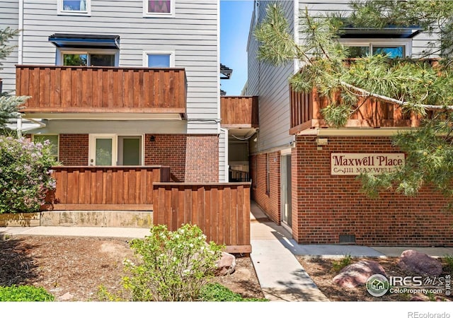 rear view of property with a balcony and brick siding