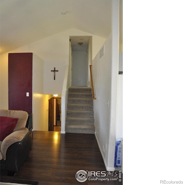 staircase with wood finished floors, vaulted ceiling, and baseboards