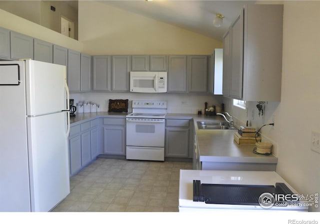 kitchen with white appliances, a sink, vaulted ceiling, light countertops, and gray cabinetry