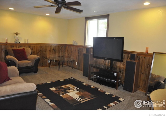 carpeted living area with a ceiling fan, a wainscoted wall, recessed lighting, and wooden walls