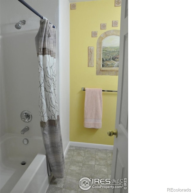 bathroom featuring shower / bath combo and baseboards
