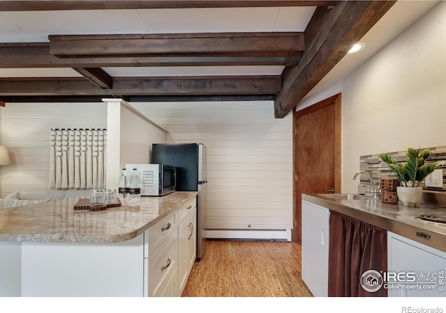 kitchen featuring a baseboard heating unit, beamed ceiling, stainless steel microwave, white cabinets, and light wood-style flooring