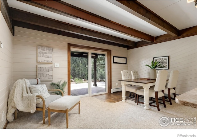 carpeted dining space featuring beamed ceiling, wood walls, and a baseboard radiator