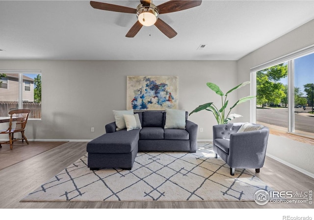 living area with plenty of natural light, wood finished floors, and baseboards