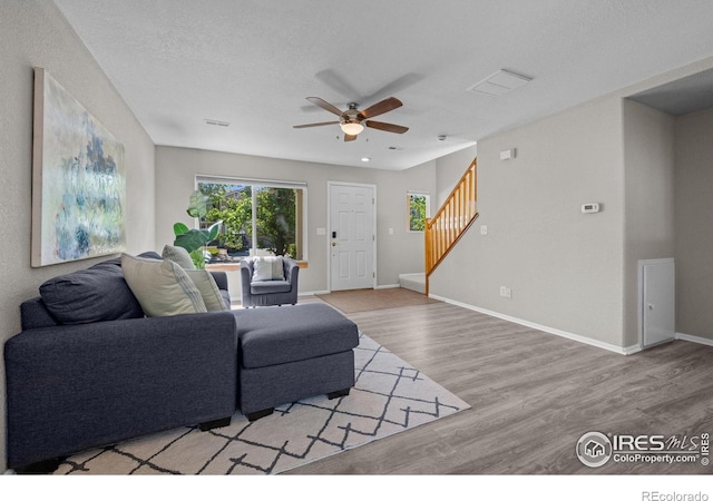 living area with ceiling fan, stairway, wood finished floors, and baseboards