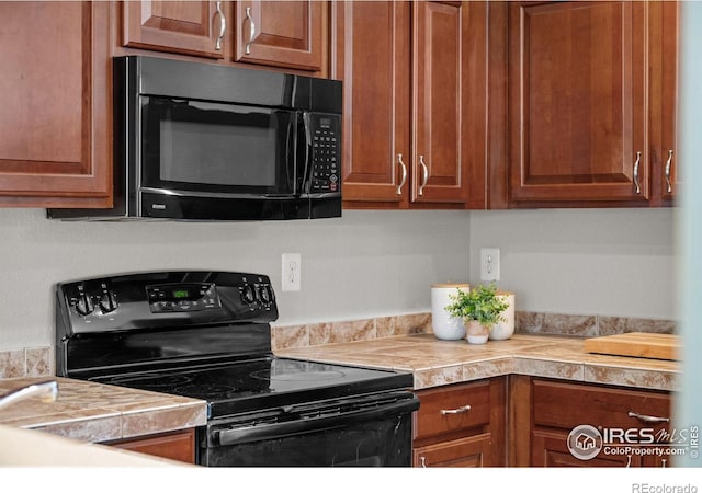 kitchen with black appliances, brown cabinets, and tile counters