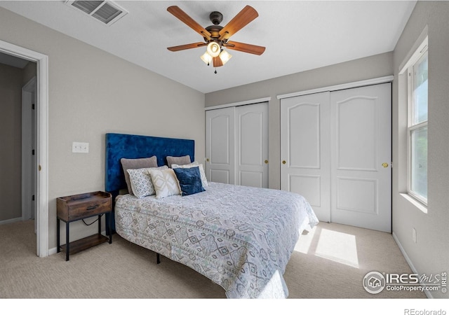 bedroom featuring multiple closets, carpet flooring, baseboards, and a ceiling fan