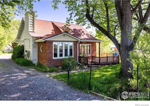 4743 Jay Rd, Boulder, CO 80301 - view of front of home with a chimney, a deck, brick siding, and driveway