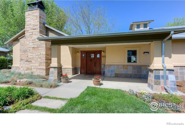 23111 County Road 1, Berthoud, CO 80513 - view of exterior entry with stone siding, stucco siding, and a chimney