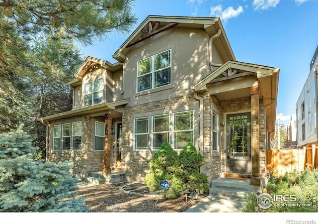 view of front facade with stone siding, stucco siding, and fence