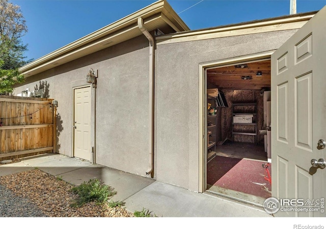 property entrance with stucco siding and fence