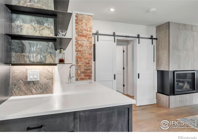 kitchen with a sink, a barn door, open shelves, light wood-style flooring, and recessed lighting
