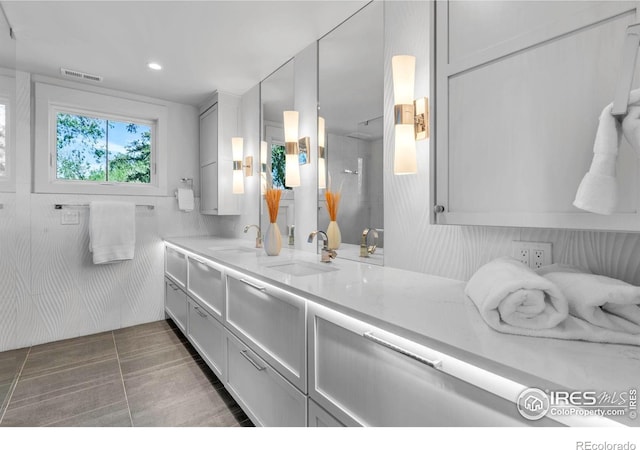 bathroom with double vanity, recessed lighting, and a shower