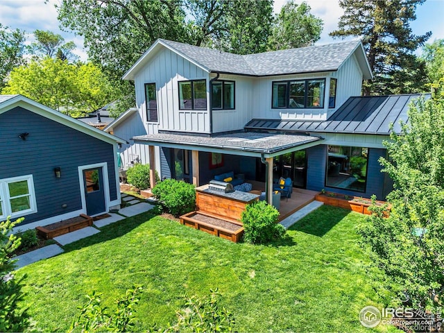 rear view of property with a standing seam roof, board and batten siding, a shingled roof, and a lawn
