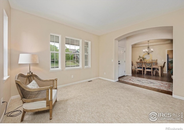sitting room featuring arched walkways, carpet, and baseboards