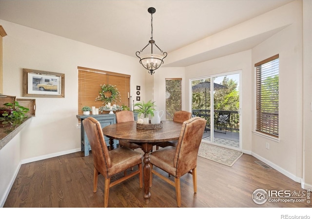 dining space featuring wood finished floors, baseboards, and a chandelier
