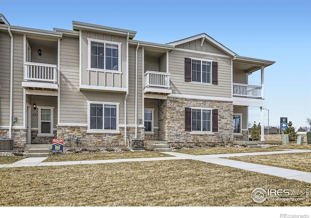 townhome / multi-family property with board and batten siding, stone siding, and a balcony