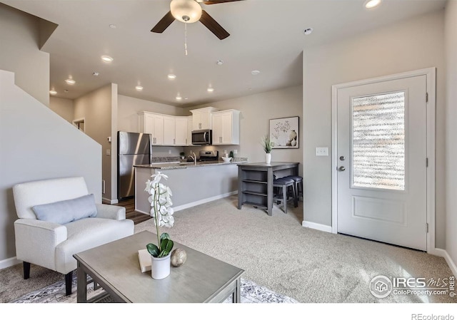 living room with ceiling fan, baseboards, light colored carpet, and recessed lighting