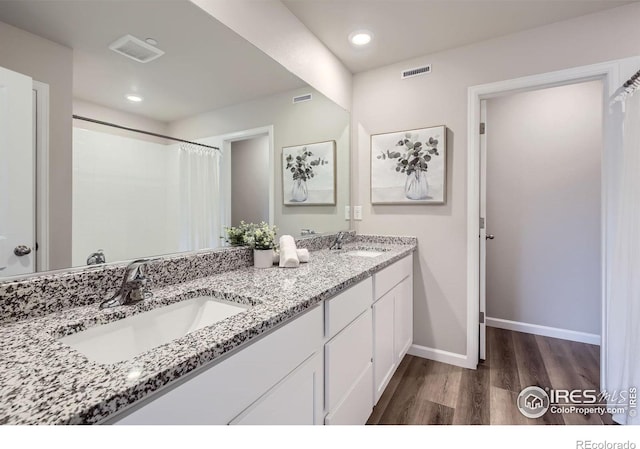 full bathroom with wood finished floors, baseboards, double vanity, and recessed lighting