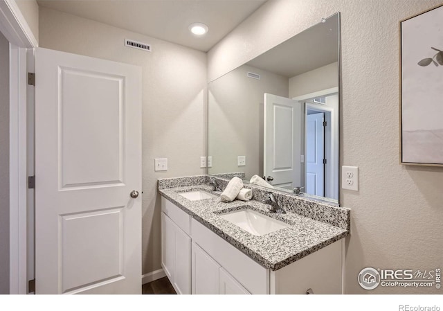 bathroom with double vanity and a textured wall