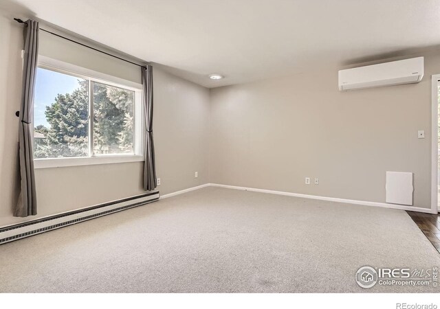carpeted spare room with a wall unit AC, a baseboard radiator, and baseboards