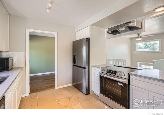 kitchen with appliances with stainless steel finishes, under cabinet range hood, white cabinetry, light countertops, and ceiling fan