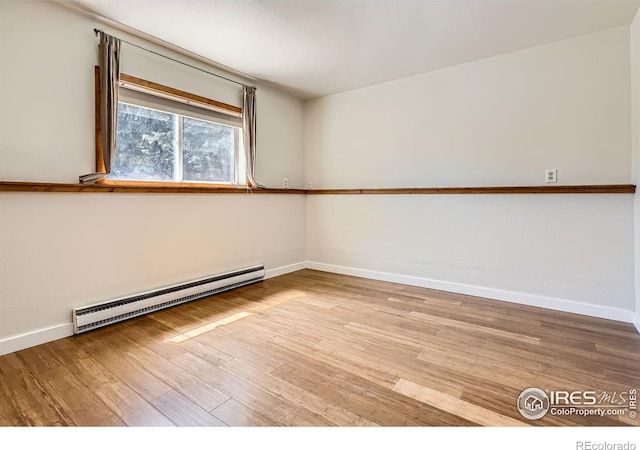 spare room featuring a baseboard radiator, wood finished floors, and baseboards