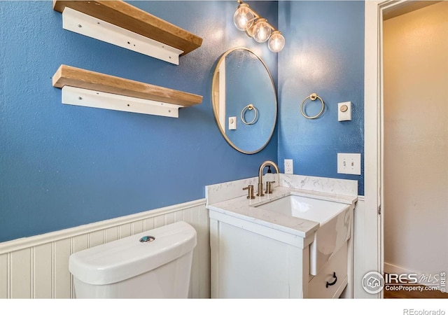 bathroom featuring a wainscoted wall, vanity, and toilet