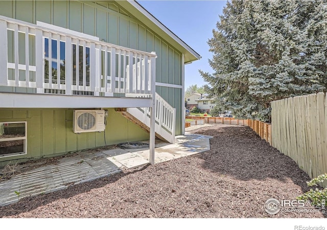 view of side of property featuring fence, board and batten siding, and ac unit