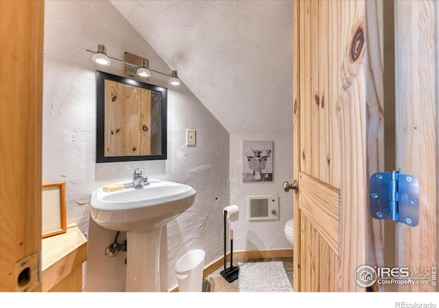 1057 Reed Ranch Rd, Boulder, CO 80302 - half bathroom featuring vaulted ceiling, a textured wall, and toilet