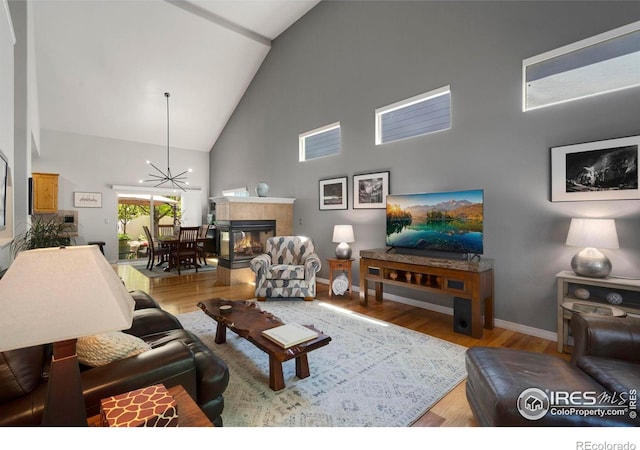 641 Yukon Ct, Windsor, CO 80550 - living area with high vaulted ceiling, baseboards, a fireplace, wood finished floors, and a chandelier