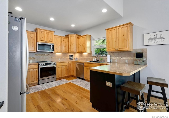 641 Yukon Ct, Windsor, CO 80550 - kitchen featuring appliances with stainless steel finishes, a sink, a peninsula, a kitchen bar, and backsplash