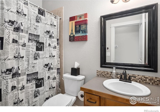 bathroom with toilet, vanity, a shower with curtain, and a textured wall