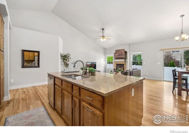 kitchen with a sink, a ceiling fan, light wood-type flooring, vaulted ceiling, and stainless steel dishwasher