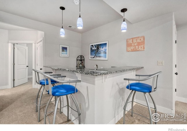 kitchen with light colored carpet, baseboards, a breakfast bar, and stone countertops