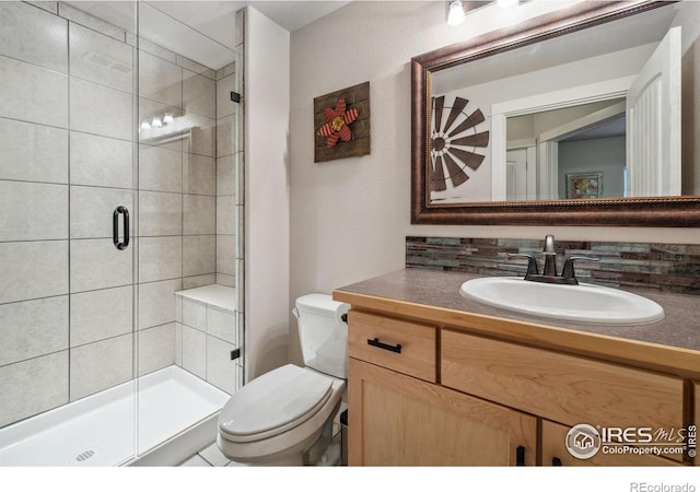 full bathroom featuring a stall shower, toilet, and vanity