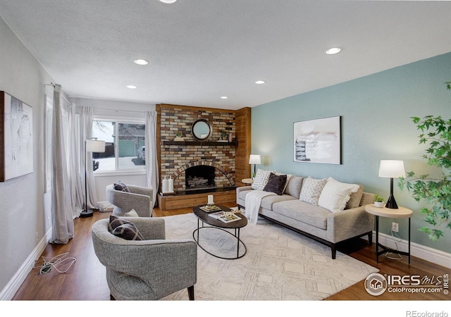 living room featuring wood finished floors, a fireplace, recessed lighting, baseboards, and a textured ceiling